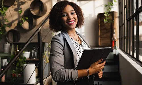 Smiling professional woman holding tablet indoors.